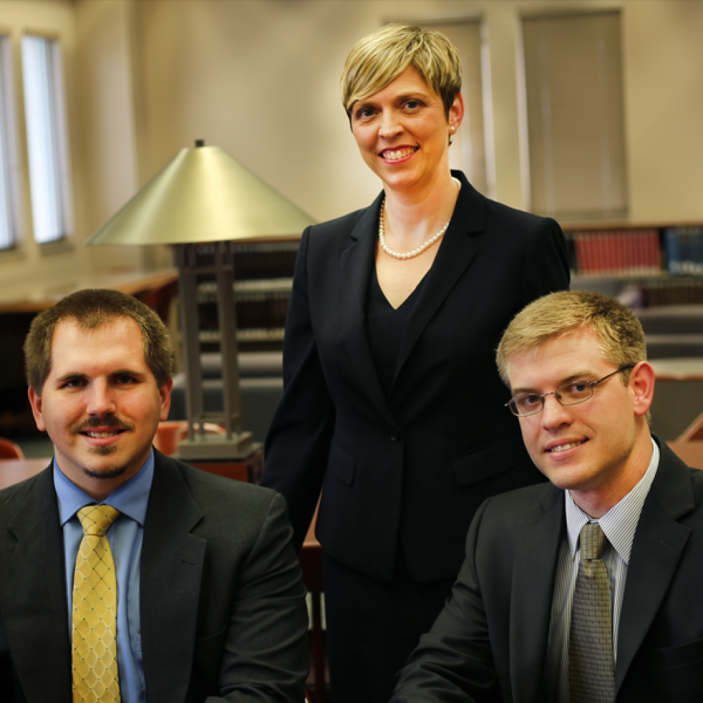 Recent UT Law graduates CJ Lewis and Thomas Smith (seated) represented Quince in his federal clemency case, with supervision from professor Joy Radice (standing).